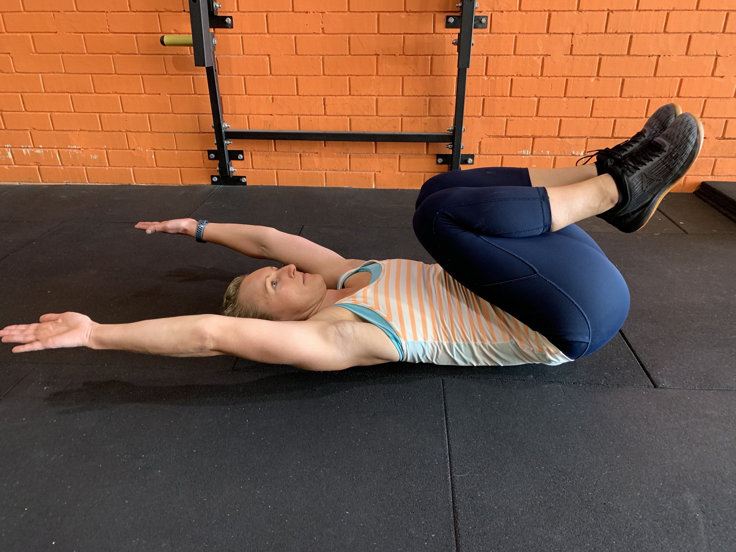 Lie on your back with your knees to your chest and your arms overhead. If your wrists don’t reach the floor, there is some shoulder tightness.