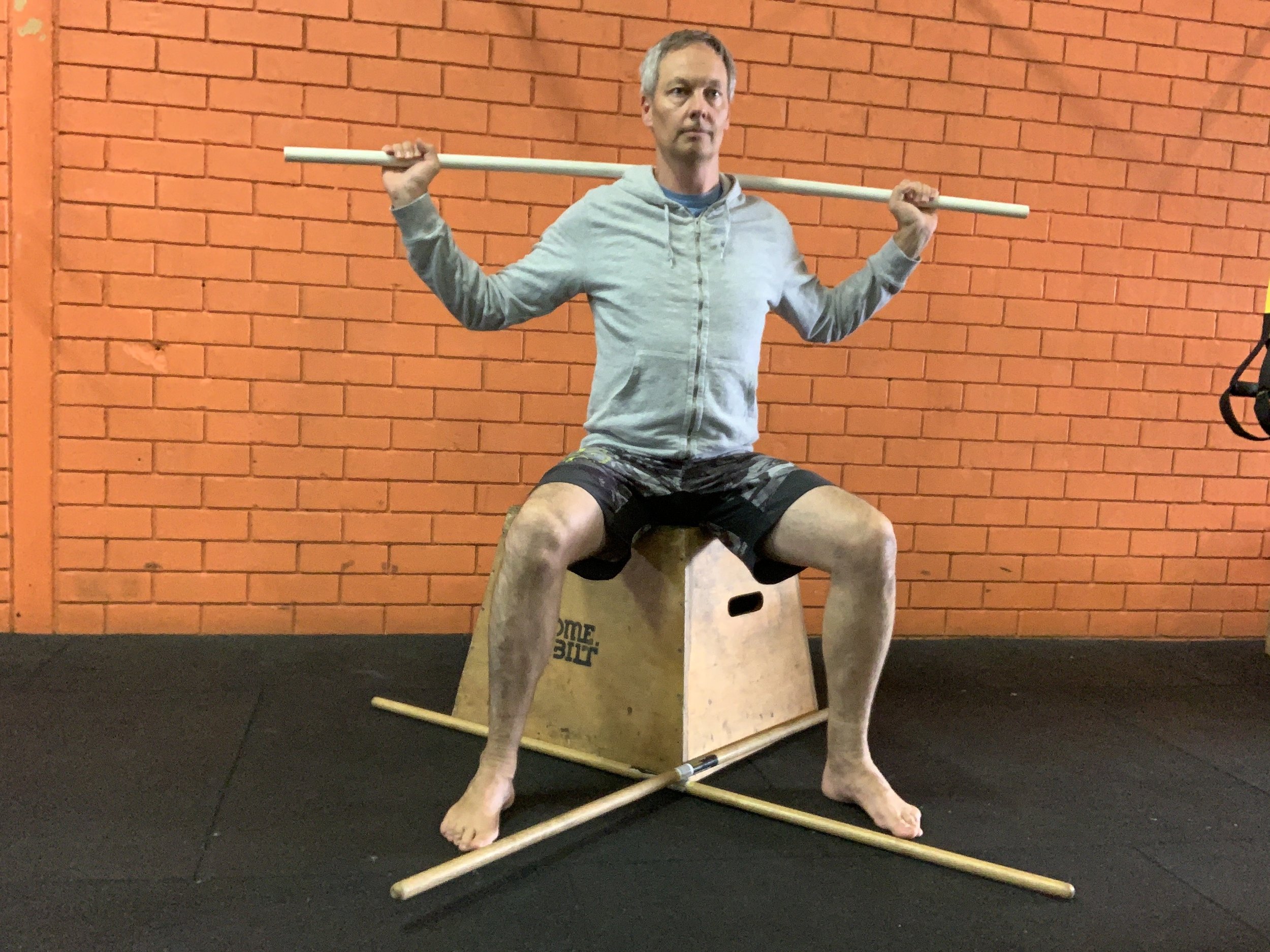 Sit on a box or bench, with two sticks at right angles at your feet, so that they point to the diagonals. This creates 45 degree lines from your midline.